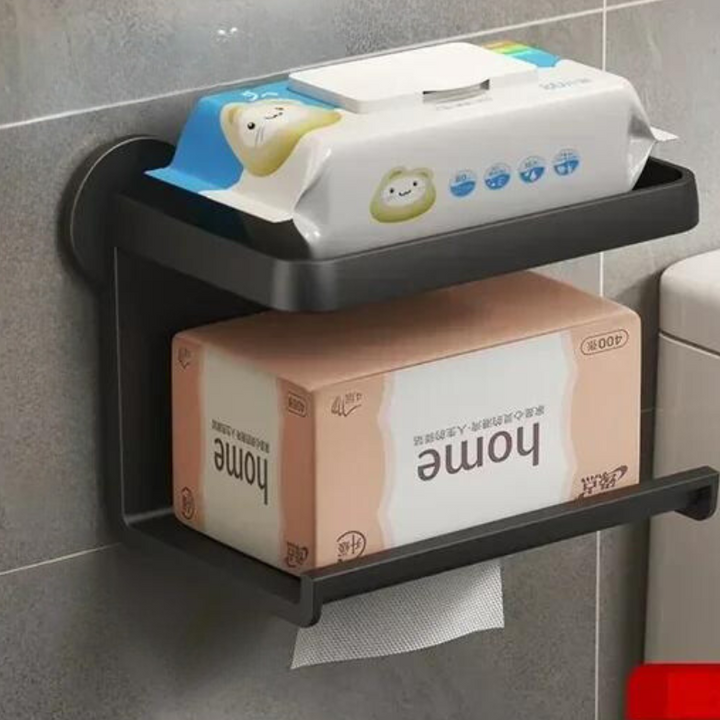 A black, moisture-resistant wall-mounted bathroom shelf holds a package of baby wipes on top and a box of tissues labeled Home below, with tissues dispensing through an opening—ideal for a multi-functional shelf with no drill installation.