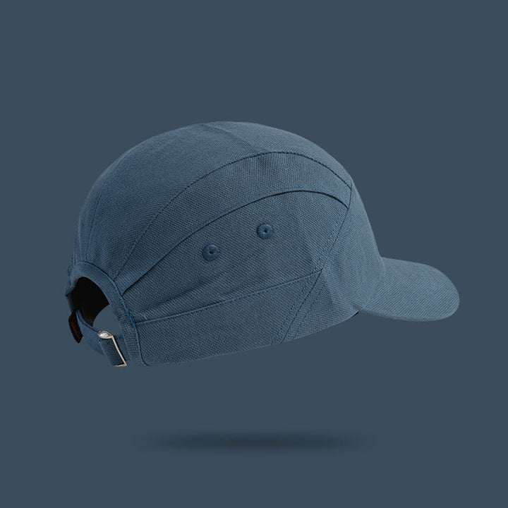 A blue unisex cap with a curved brim and adjustable strap, inspired by Japanese-style peaked cap designs. The metal clasp, stitching, and eyelets are visible against a solid blue background.