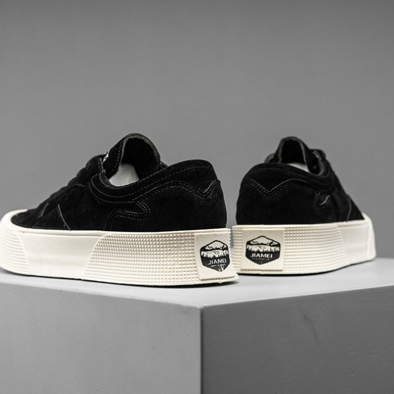 A pair of black suede lace-up sneakers with thick white soles and a JIAMEI label on the heel, featuring comfortable cushioning, displayed on a gray platform against a plain gray background.
