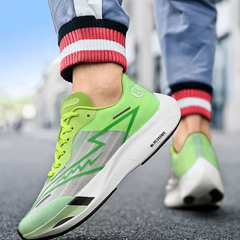 A close-up of a person wearing neon green athletic running shoes with white shock-absorbing soles and lightning bolt designs, standing on a city street. The person is dressed in blue pants with red and white striped cuffs.