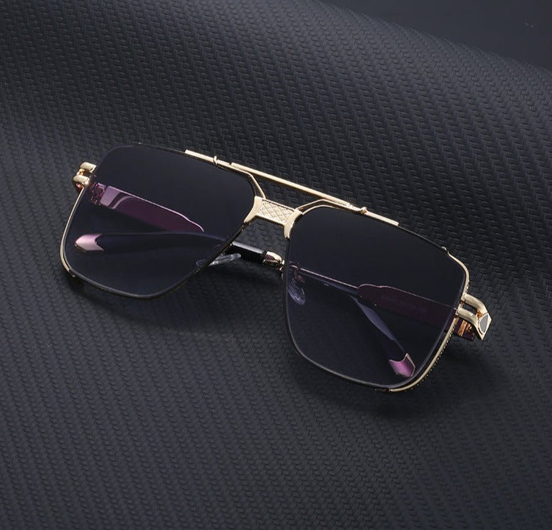 A pair of stylish, gold-rimmed vintage sunglasses with dark lenses and UV400 protection is placed on a textured black surface.
