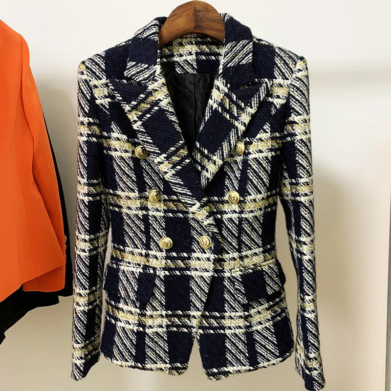 A navy blue and white plaid wool tweed double-breasted blazer with gold buttons is hanging on a wooden hanger next to an orange garment.