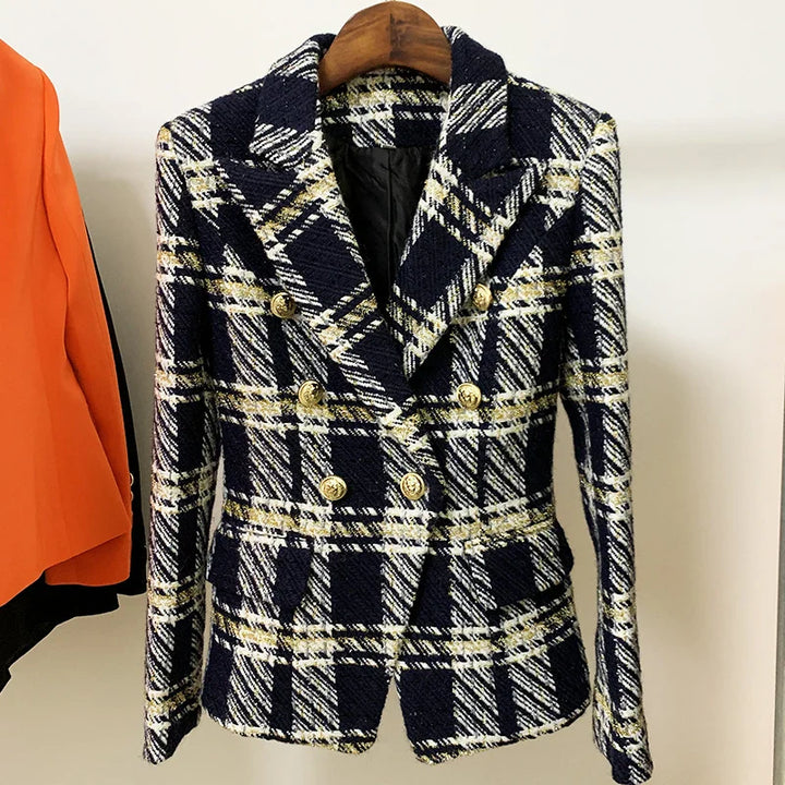 A navy blue and white plaid wool tweed double-breasted blazer with gold buttons is hanging on a wooden hanger next to an orange garment.