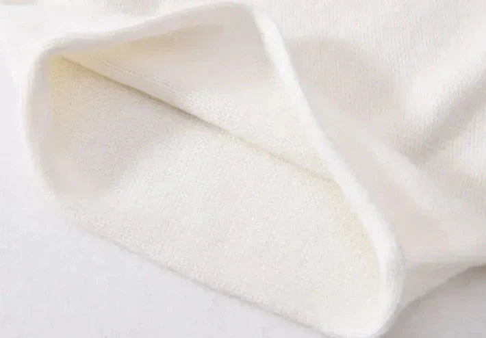 A close-up of a piece of white, soft, fleece fabric, showing its folded edge and textured, fluffy surface—reminiscent of cashmere in its lightweight warmth and plush feel.