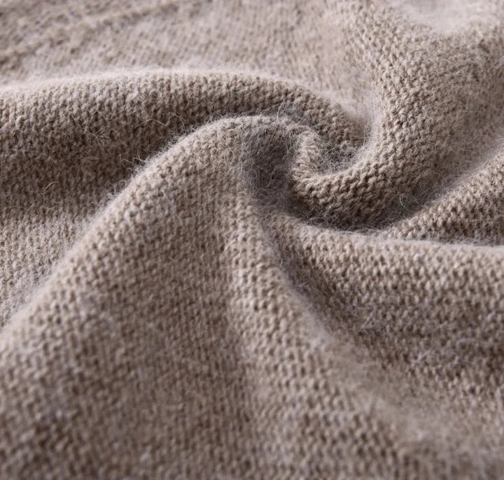 Close-up of a soft, beige cashmere knitted fabric with a visible swirl fold, showing the lightweight texture and fine fibers of the material.