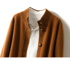 A brown ultra soft cashmere cardigan with a ribbed collar is layered over a white collared shirt, both hanging neatly against a white background.