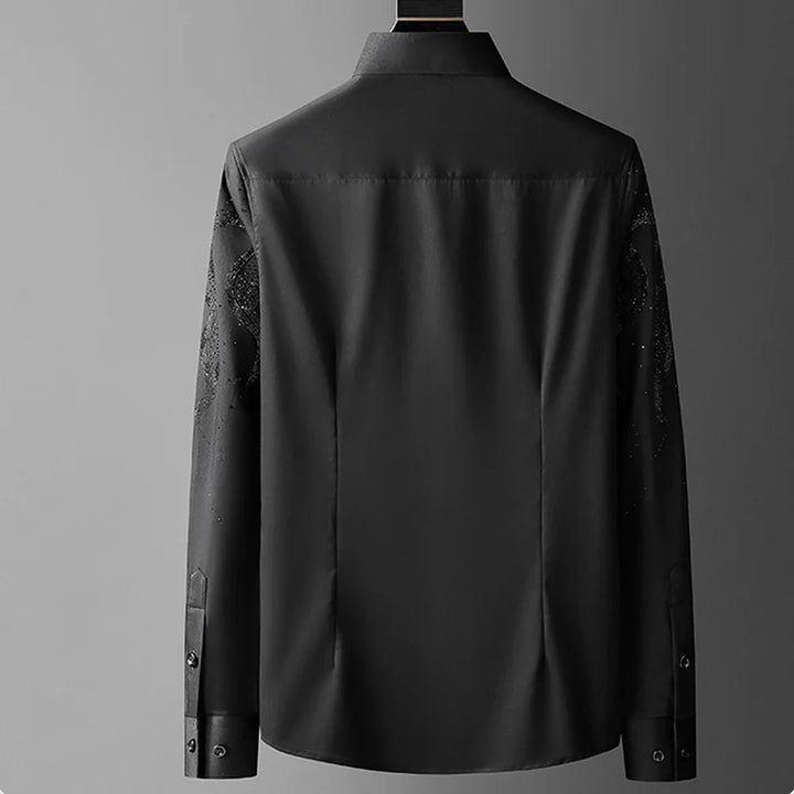 A black tailored fit button-up shirt is shown from the back against a plain gray background. The shirt features a classic collar and buttoned cuffs, with subtle patterns visible on the sleeves for added detail.