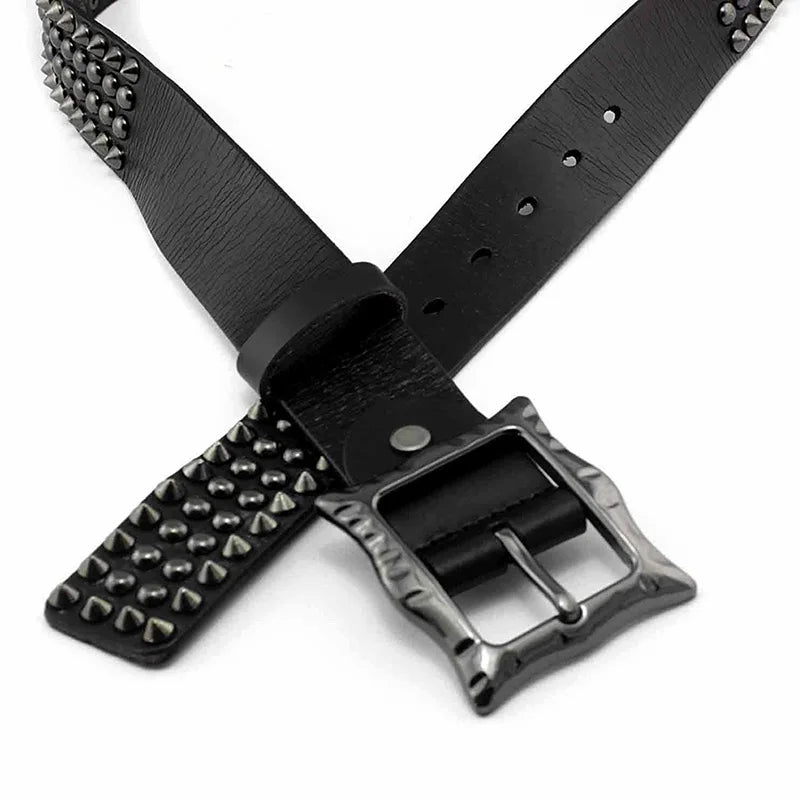 Black leather studded belt with silver pyramid-shaped studs and a textured, adjustable buckle, highlighted by its durable leather construction and striking studded detailing, displayed in a crisscross arrangement on a white background.