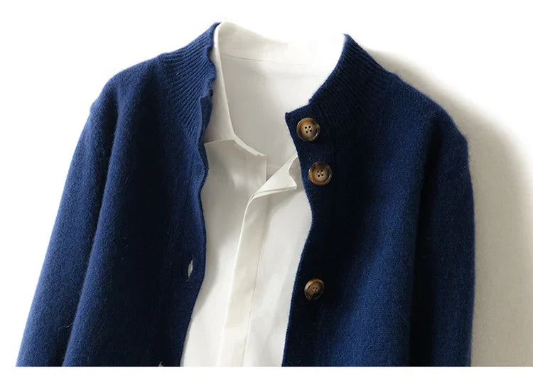 A close-up of an ultra soft navy blue cashmere cardigan with brown buttons, partially buttoned over a white collared shirt. The garments are laid flat against a white background.