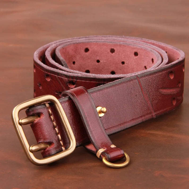 A rolled-up vintage leather belt with multiple holes, a brass buckle, and a small brass ring, placed on a brown surface.