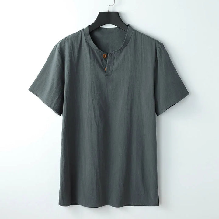 A plain, short-sleeved, dark gray Japanese linen shirt with a round collar and two brown buttons near the neckline hangs on a black hanger against a white background—perfectly lightweight and breathable for summer.