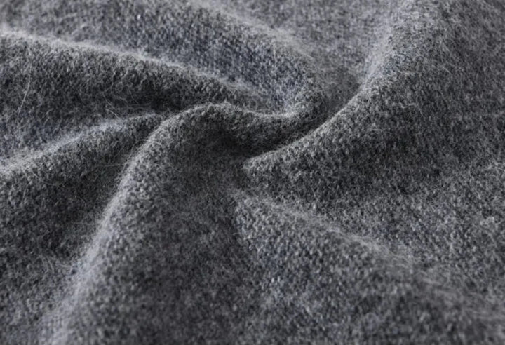 Close-up of soft, textured gray wool fabric with visible fibers and gentle folds, evoking the cozy feel of a lightweight slouchy beanie.