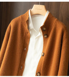 A white collared shirt on a hanger layered under an ultra soft, brown, buttoned cashmere cardigan, displayed against a wooden background.
