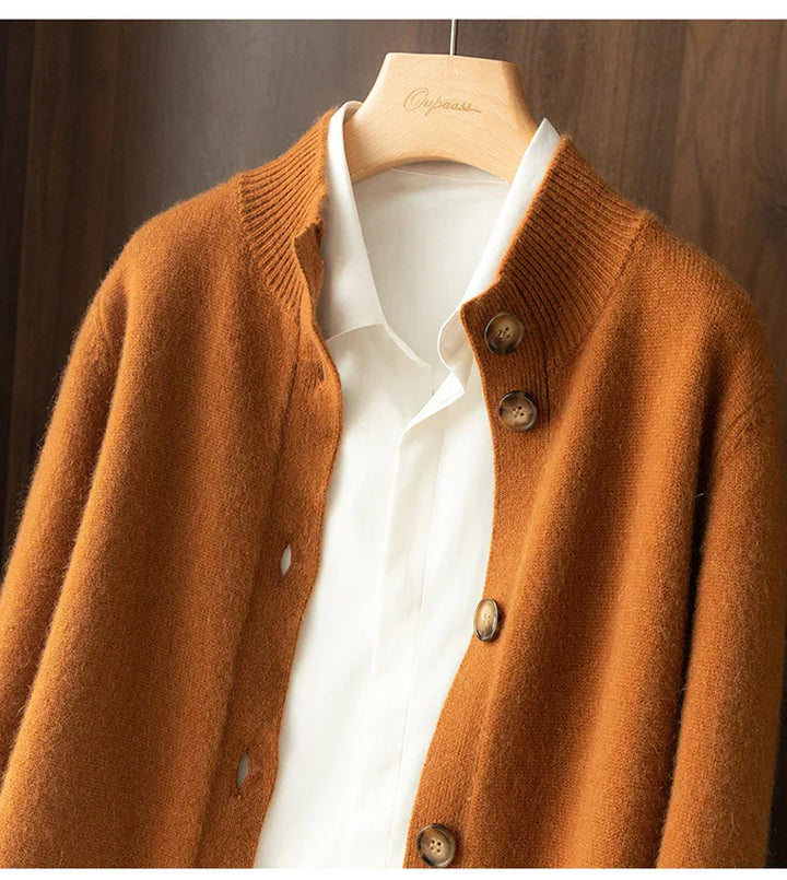A white collared shirt on a hanger layered under an ultra soft, brown, buttoned cashmere cardigan, displayed against a wooden background.