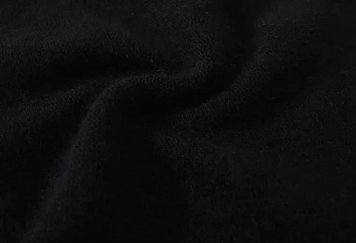 Close-up of a piece of soft, black cashmere fabric with gentle folds and a slightly textured surface, creating subtle shadows and highlights.