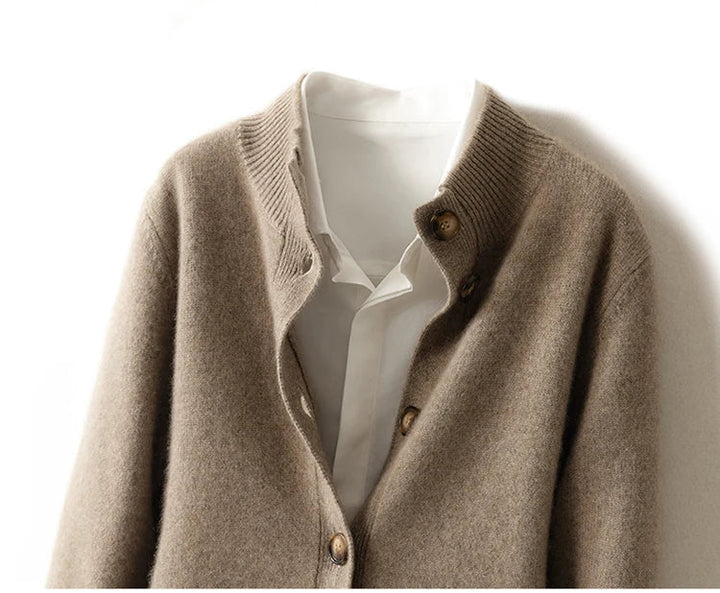 An ultra soft beige knit cashmere cardigan with brown buttons layered over a white collared shirt, displayed on a hanger against a white background.