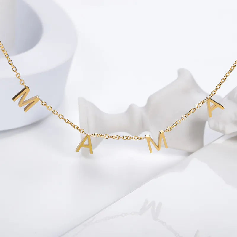 A gold minimalist jewelry piece, this stainless steel necklace features four dangling letter charms spelling MAMA, displayed against a white background with abstract white shapes.