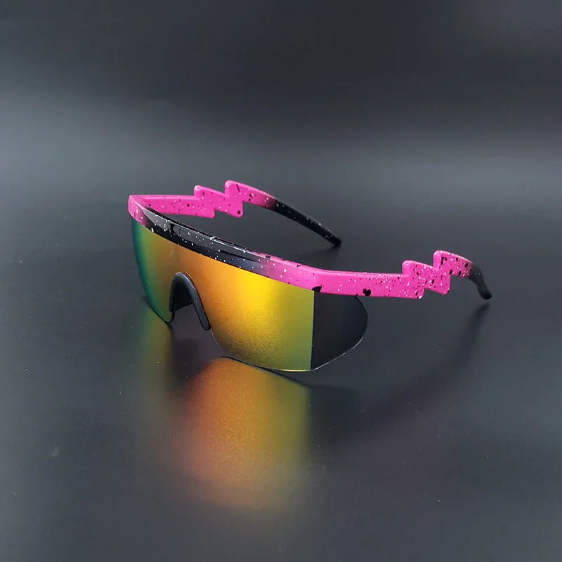 Futuristic sport sunglasses with a pink, lightning bolt-shaped frame and reflective yellow-orange lenses, these UV400 Cycling Glasses are displayed on a dark, glossy surface.
