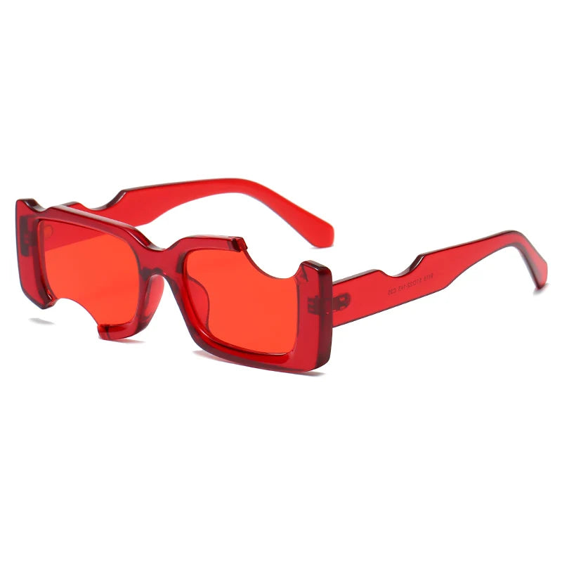 Red, rectangular sunglasses with thick geometric frames and matching red tinted lenses, featuring unique notches on the top and bottom edges. Their futuristic design and bold red arms make them a standout accessory for street style looks.