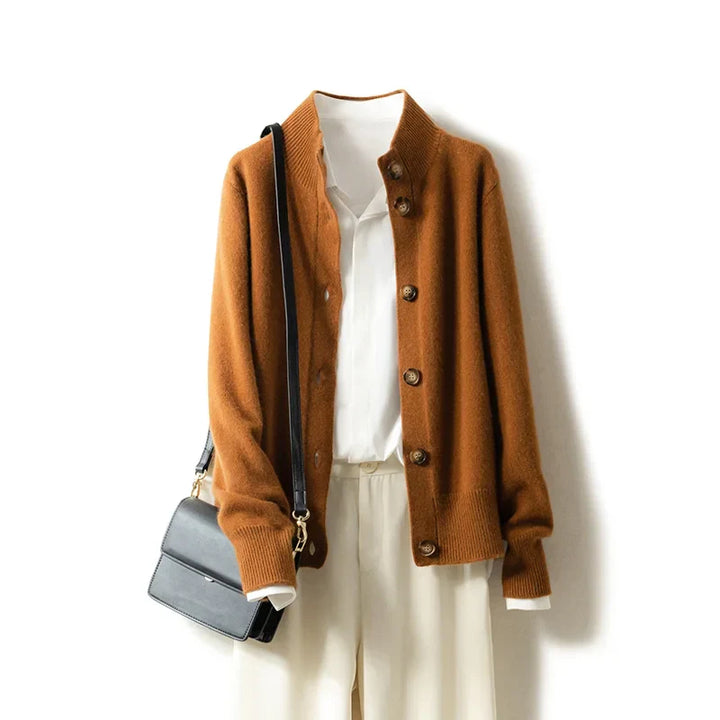 An ultra soft brown cashmere cardigan, layered over a white collared shirt and cream pants, with a black shoulder bag hanging from the shoulder, displayed against a white background.