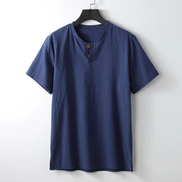 A plain, short-sleeved navy blue shirt crafted from lightweight breathable Japanese linen with a round neckline and two brown buttons on a short placket, hanging on a black hanger against a white background—perfect for summer.
