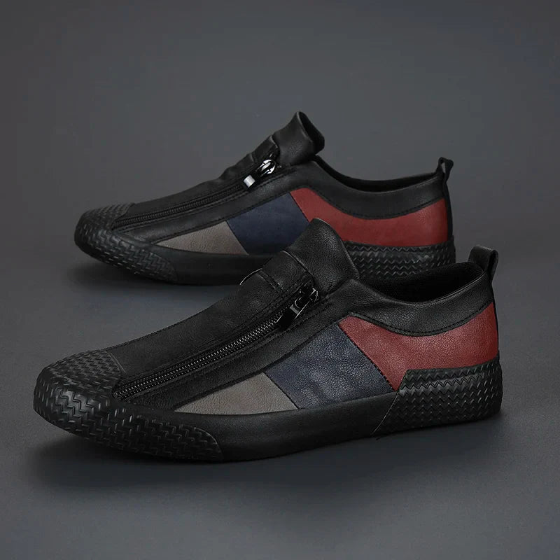 A pair of stylish low-top slip-on sneakers with zipper closure and side zippers. The shoes feature black soles and uppers with dark red, navy blue, and gray color blocks on the sides, plus a textured toe and heel.