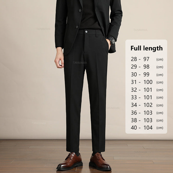 A man in a black suit and brown dress shoes stands with his hands in his pockets, showcasing Mens Slim Casual Trousers. Next to him is a chart listing pant full-length sizes in centimeters, ranging from size 28 (97 cm) to size 40 (104 cm).