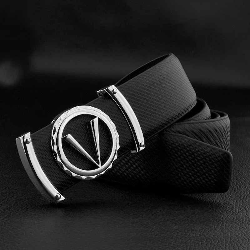 A black full-grain leather belt with a large, round silver buckle featuring a bold, stylized V design, displayed on a dark surface. The adjustable fit ensures comfort and versatility for any look.