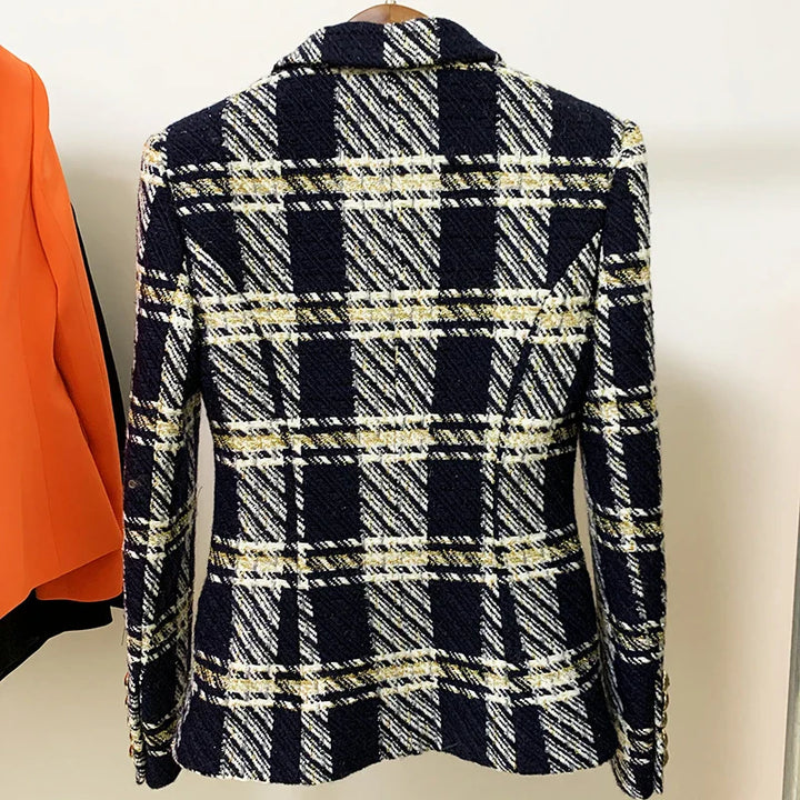 A navy blue and white plaid wool tweed blazer with yellow accents is displayed on a hanger, seen from the back. This slim fit designer jacket features part of an orange garment visible to the left.