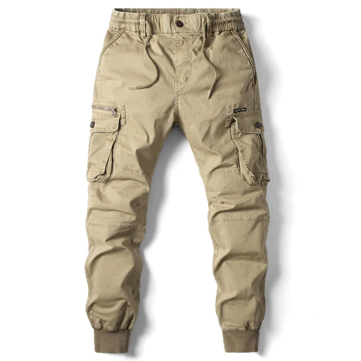 Beige tactical pants featuring cargo pockets, an elastic waistband with drawstring, and ribbed cuffs at the ankles—perfect for effortless street style. Laid flat on a white background.