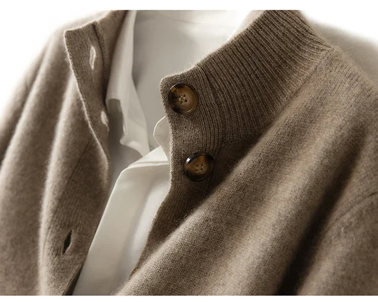 Close-up of an ultra soft cashmere cardigan in beige with brown buttons over a white collared shirt, highlighting the texture of the 100% wool cashmere fabric and details of the buttoned collar.