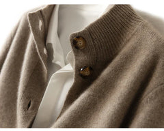 Close-up of an ultra soft cashmere cardigan in beige with brown buttons over a white collared shirt, highlighting the texture of the 100% wool cashmere fabric and details of the buttoned collar.