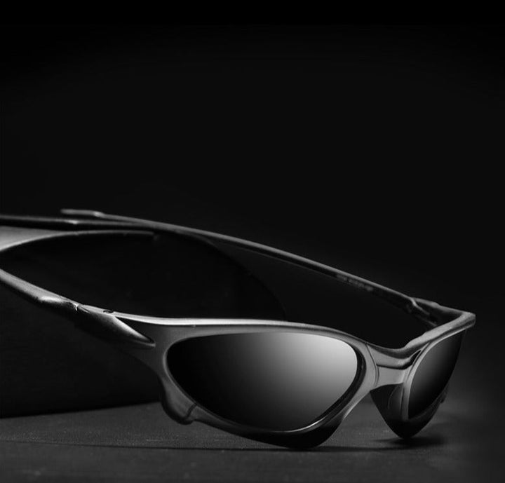A pair of dark, Sports Polarized Sunglasses with UV400 Protection is placed on a black surface against a black background, creating a dramatic and stylish appearance.