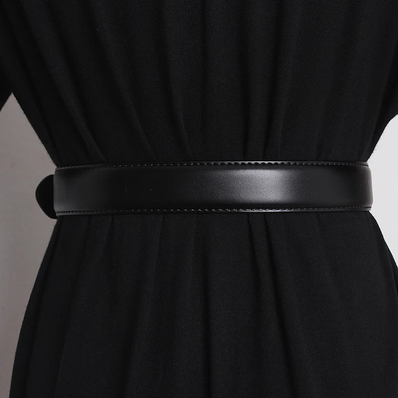 A close-up of a person wearing a black outfit with a wide, smooth genuine leather belt cinched around the waist. The material appears soft and the belt has a subtle stitched edge.