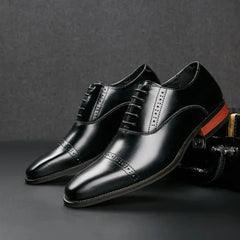 A pair of polished black Italian leather dress shoes with decorative stitching, cap toes, and a distinctive orange detail on the heel, featuring elegant hand-stitched detailing, displayed against a dark background.