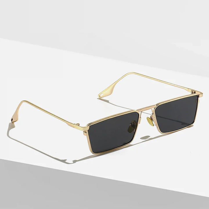 A pair of Avalon Sunglasses featuring rectangular lenses with thin gold frames and dark lenses rests on a white and gray surface, casting a shadow.