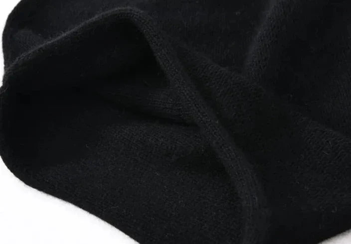 A close-up of a soft, black piece of cashmere fabric with a slightly fuzzy texture, loosely folded on a white background.