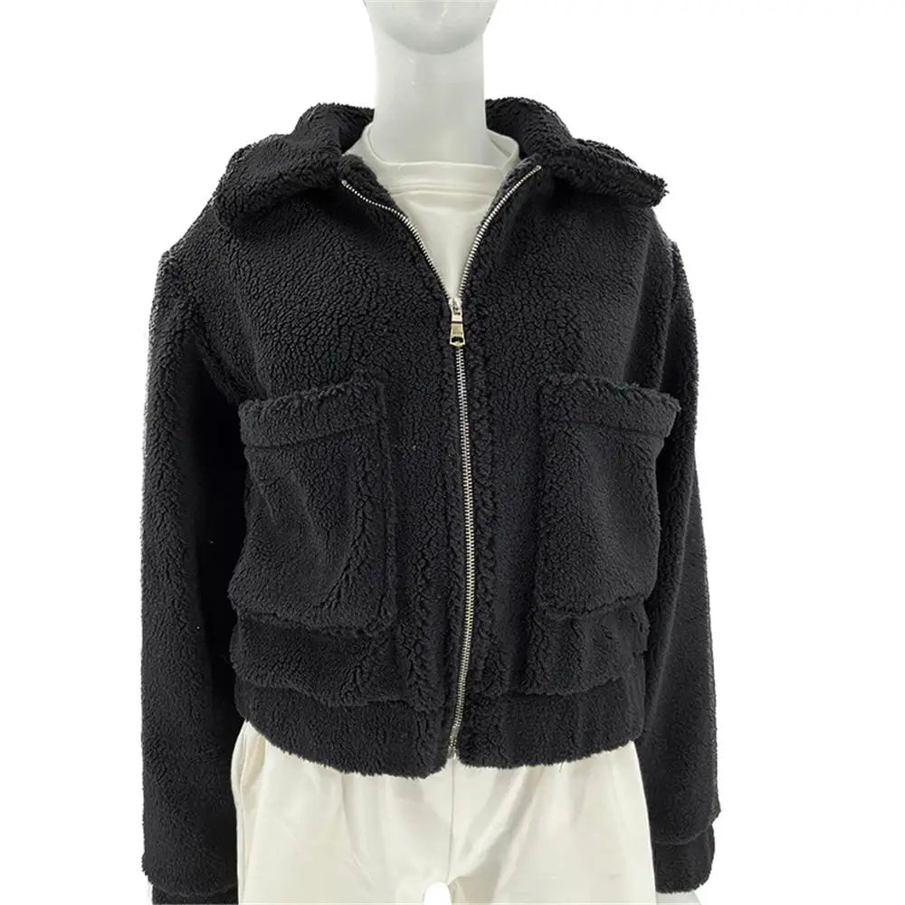 A mannequin wearing a black, zip-up, cropped sherpa fur jacket with large front pockets over a plain white shirt—perfect for all season layering.