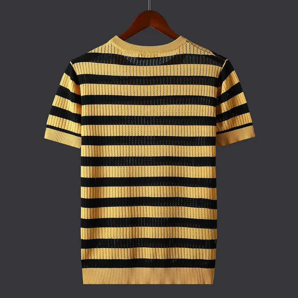 A short-sleeve knit shirt with horizontal yellow and black stripes, crafted from a silk cotton blend, displayed on a wooden hanger against a dark background. The shirt features a ribbed neckline, sleeves, and hem.