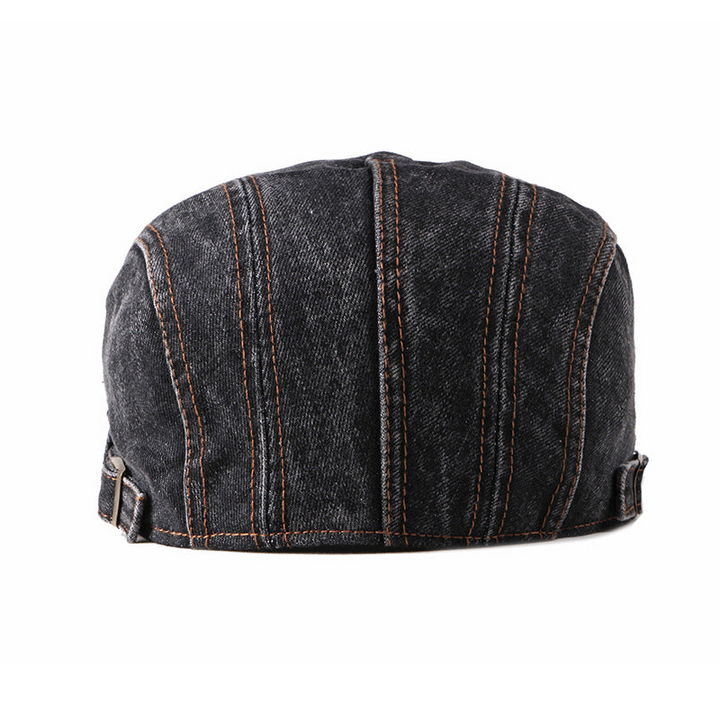 A black premium denim flat cap viewed from the back, featuring vertical brown stitching and adjustable straps on both sides.