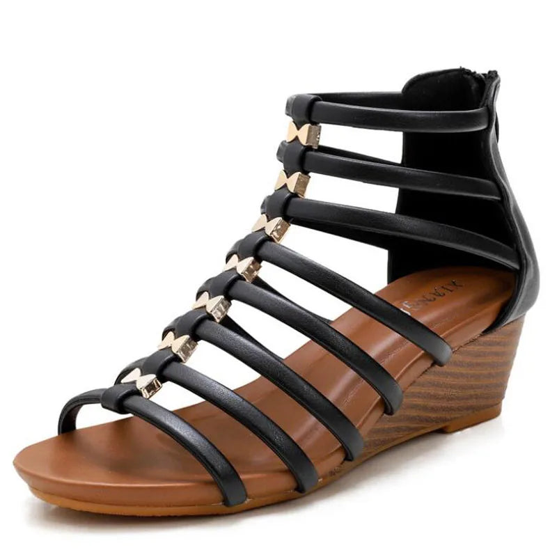 A black gladiator wedge women shoes with multiple horizontal straps, gold accents, a tan cushioned footbed, and a brown wood-textured low wedge heel. The sandal features a closed back with zipper and is available in plus size options.
