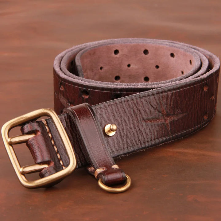 A coiled dark brown vintage leather belt with a textured finish, featuring a large brass buckle and multiple adjustment holes, placed on a wooden surface.