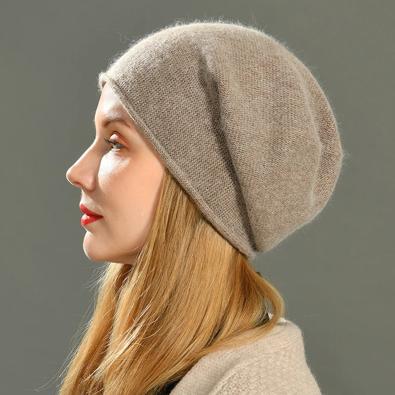 A woman with long blonde hair, wearing a light brown slouchy beanie, is shown in profile against a plain gray background.