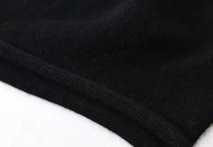 Close-up of a black cashmere fabric with a visible seam along the edge, laying on a white surface. The texture of the fabric appears soft and slightly fuzzy.