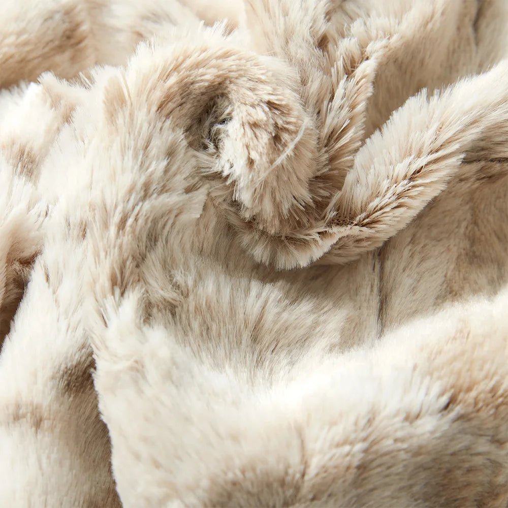 Close-up of ultra-soft luxurious blanket in beige faux fur, showcasing its plush, fluffy texture and subtle color variations, with wavy folds and gentle shadows.