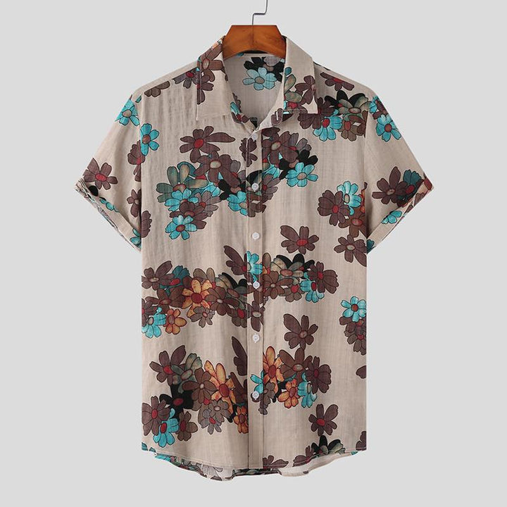 A short-sleeved, beige Mens Hawaiian Shirt with a collar, featuring vibrant flower prints in brown, blue, and red hues, hanging on a wooden hanger against a plain background—a perfect pick for streetwear fashion.