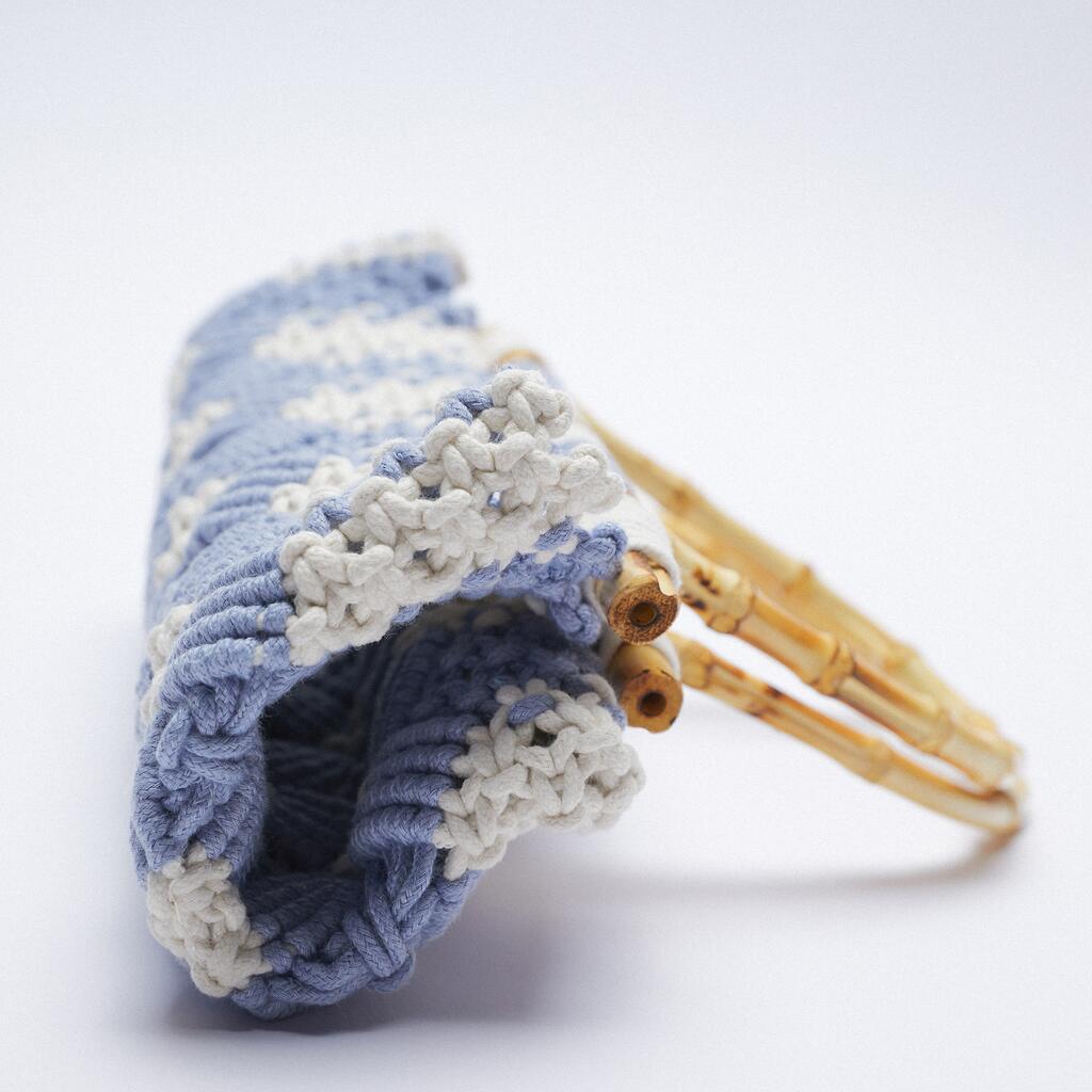 A close-up of a lightweight bag with blue and white knitted fabric and bamboo handles, set against a plain white background.