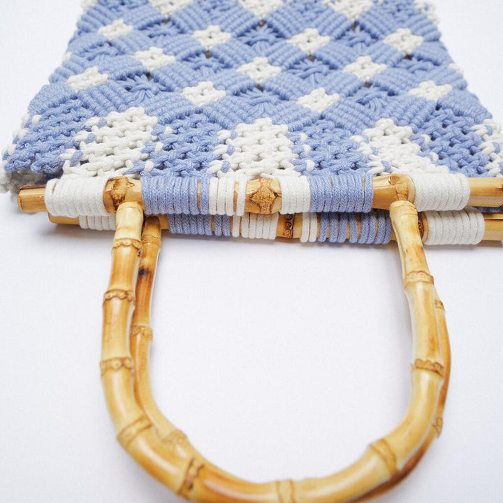 Close-up of a lightweight bag with a blue and white checkered pattern, featuring round bamboo handles, set against a plain white background.