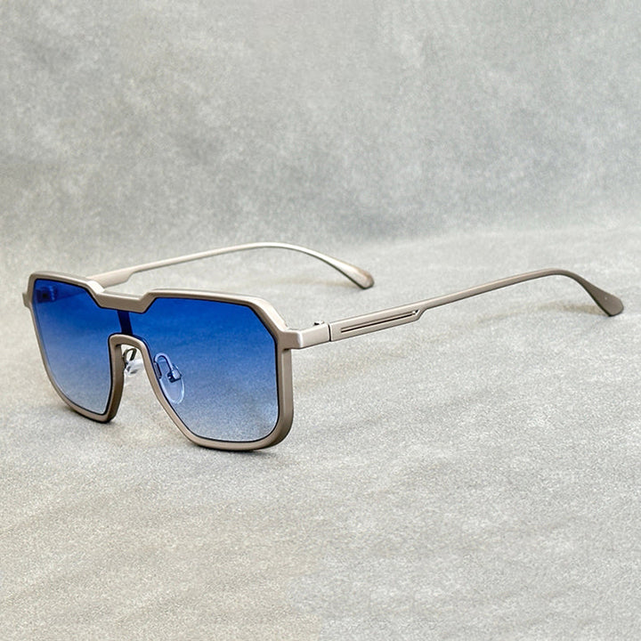 A pair of modern, geometric Heavy Metal Sunglasses with square metallic frames and blue gradient lenses rests on a light grey textured surface.