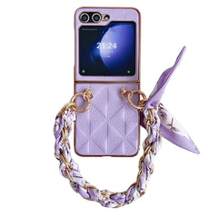 A lavender Samsung Galaxy Z Flip phone case with a geometric pattern, gold rings, a braided chain handle woven with a matching scarf, a small external screen displaying 21:24, and shockproof protection.
